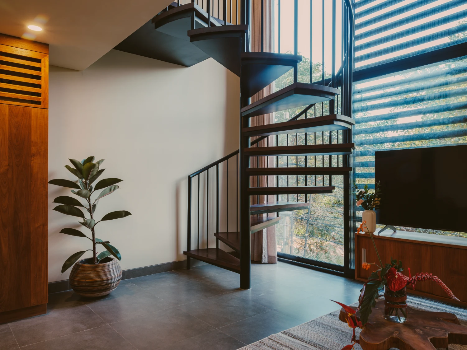 Architectural spiral staircase framed by floor-to-ceiling louvred windows