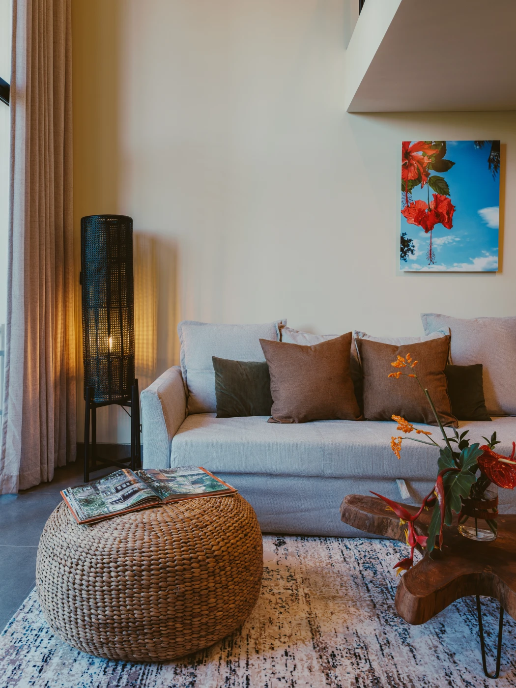 Relaxed corner lounge with woven rattan pouf and floor lamp