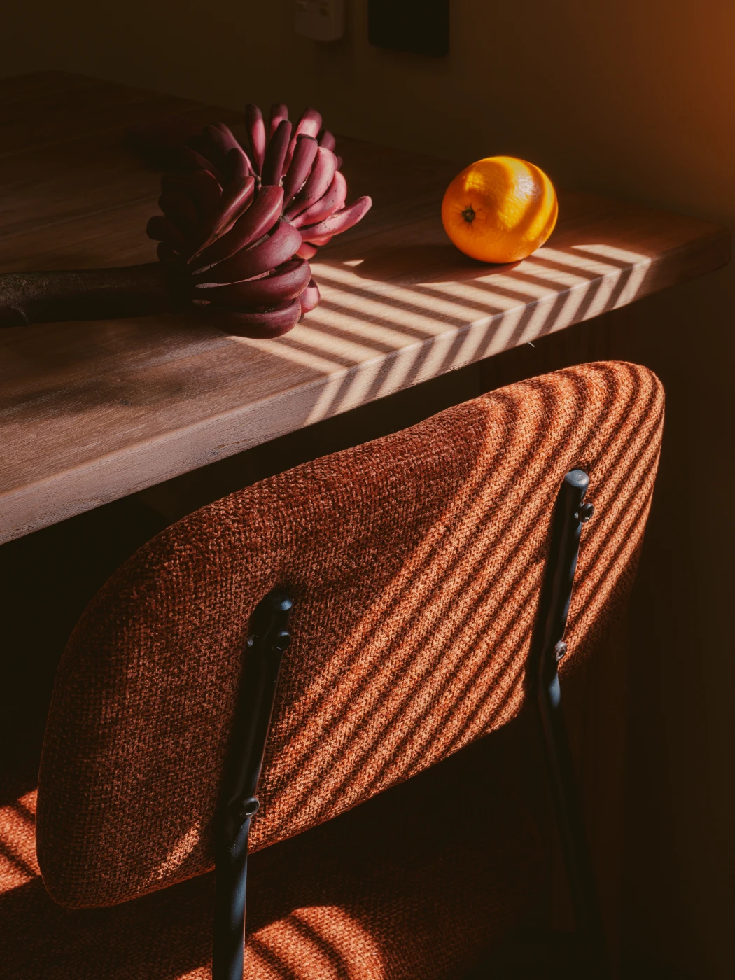 Sunlit wooden dining setting with slatted morning light and tropical fresh fruit